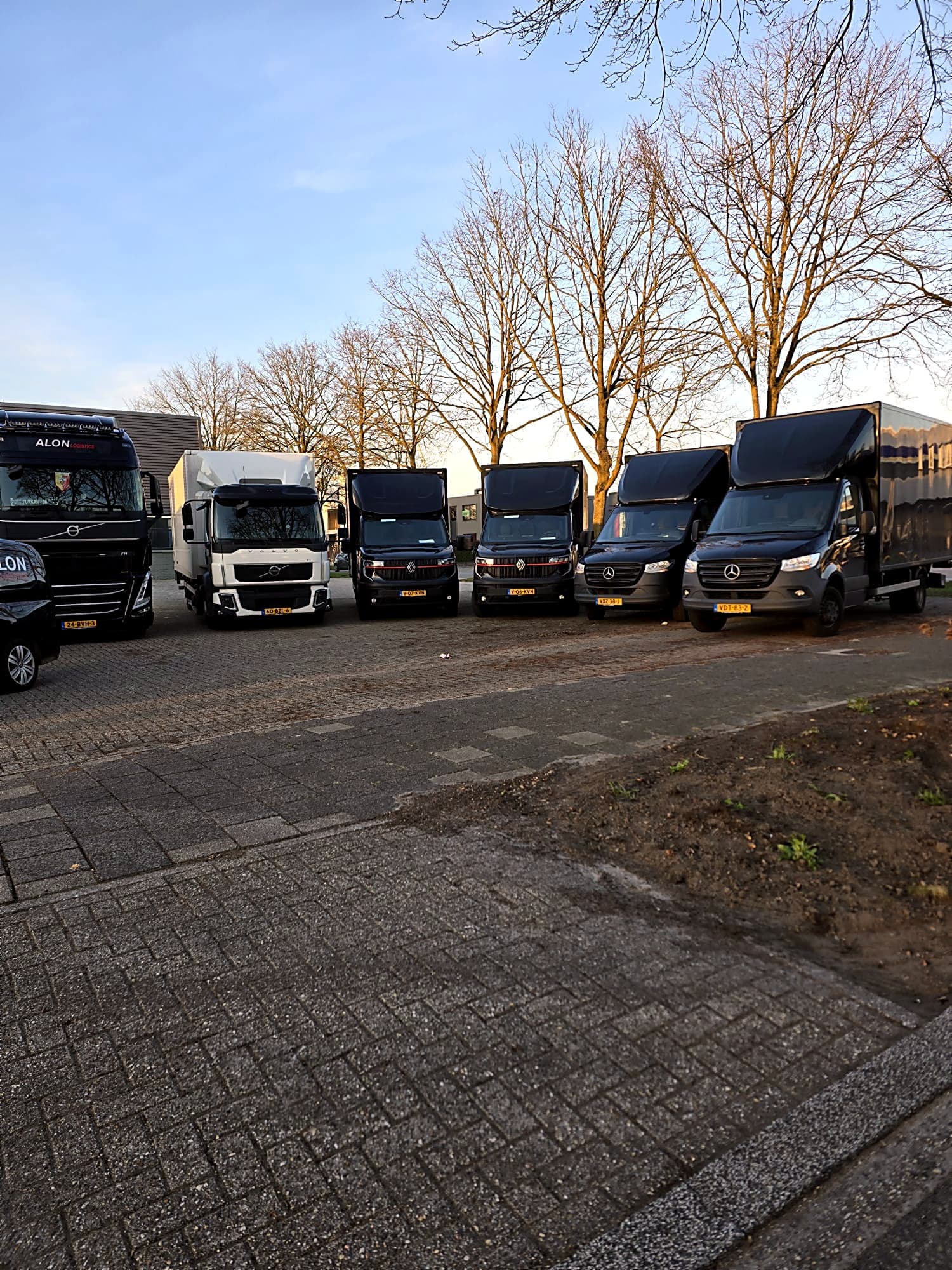 Rij bakwagens en bestelbussen op het terrein van Alon Logistics